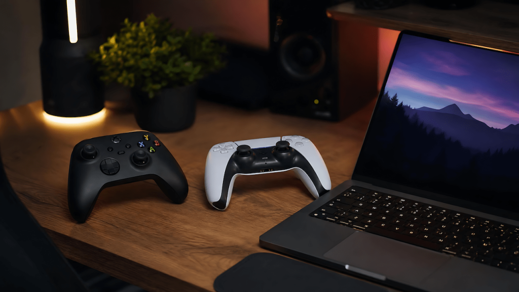 Xbox and DualSense controllers on a gaming desk next to a laptop